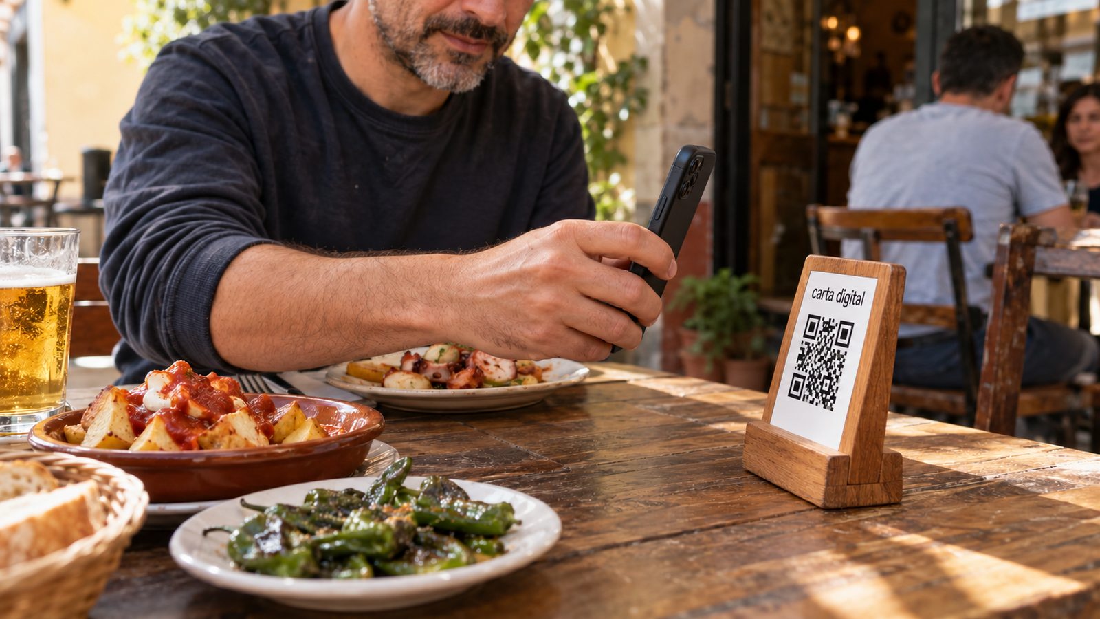 Cliente consultando con el móvil la carta digital por QR en la mesa de un bar